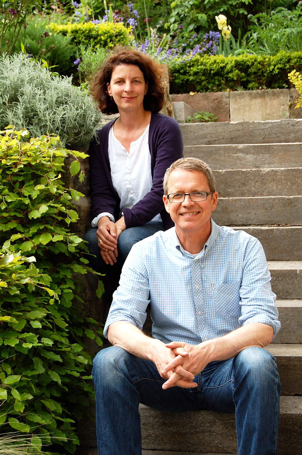 En mand og en kvinde sidder på en trappe og ser glade og afslappede ud.