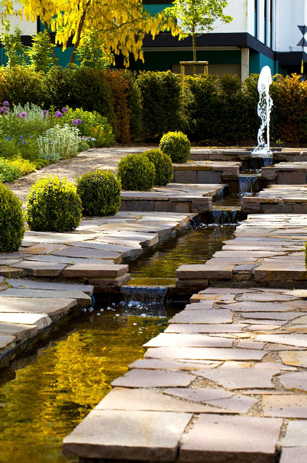 Ein Steinweg führt zu einem Brunnen in einem ruhigen Garten.